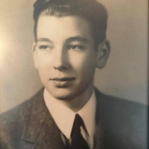 Vintage black-and-white portrait of a young man in a suit and tie. He has neatly styled hair and looks pensively to the side, conveying a reflective mood.
