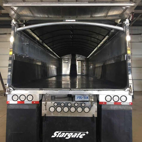 Open-back view of a large, empty Stargate truck trailer in a warehouse, with shiny metal interior and bright overhead lighting, conveying readiness.