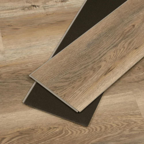 Two wooden floor tiles, one placed on top of the other, on a matching wood floor. The tiles have a light brown, natural wood grain pattern.