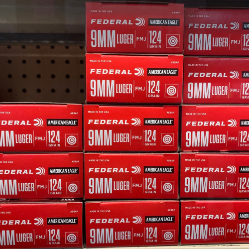 Stacked red boxes of Federal 9mm Luger 124 grain ammunition on display in a store, featuring bold white text and logos on each box front.
