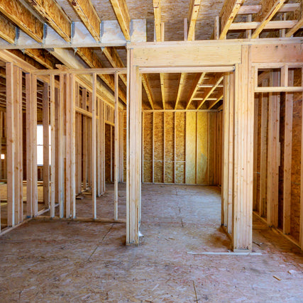 Building MaterialsWooden framing of a house under construction. Exposed studs, beams, and plywood floors and walls create a skeletal structure, evoking a sense of progress and potential.